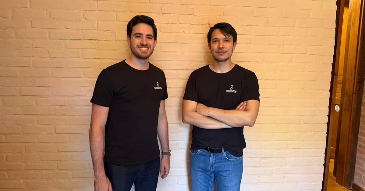 Leonardo Bock e Henrique Labella, fundadores da timeshifter, diante de uma parede de tijolos